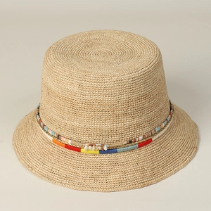 Detail of handwoven raffia bucket hat featuring a colorful ethnic band with shell accents