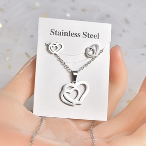 Close-up of silver stainless steel jewelry set with hollow double heart design on card