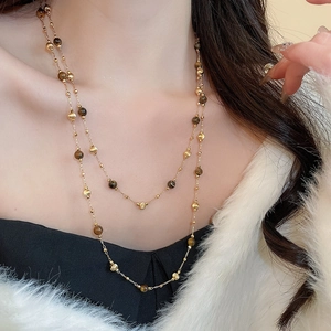 Detail of 18k gold plated double-layer necklace with tiger eye stones and pearls on a model