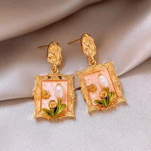 Detail of vintage square frame earrings with freshwater pearls on beige silk fabric