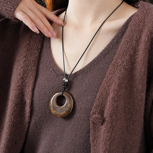 Macro shot of circular resin pendant with brown leopard texture and woven rope necklace
