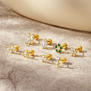 Close-up of gold S925 silver Christmas earrings with green zircon on stone surface