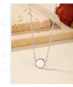 Macro detail of S925 silver necklace with round white opal pendant on stone texture
