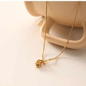 Detailed close-up of 18K gold sailor knot pendant on a sleek snake chain necklace