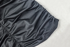 Close-up of the black ruched fabric texture with a silky sheen on this bodycon dress