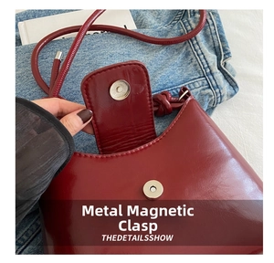 Detail shot of the dark red leather shoulder bag showing the metallic magnetic closure