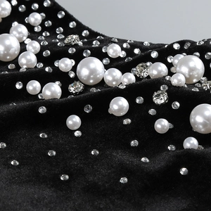 Detail of elegant black velvet fabric with white pearls and sparkling rhinestone embellishments