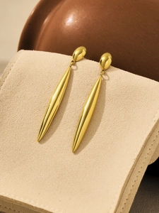 Detailed macro view of long teardrop earrings displayed on a soft beige velvet jewelry box