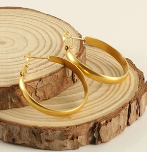 Detailed shot of matte gold hoop earrings resting on rustic wooden circles for display