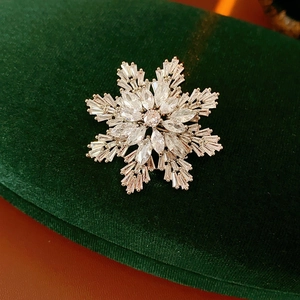 Macro detail of snowflake brooch with sparkling cubic zirconia on green velvet