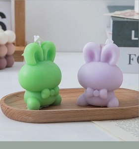 Detail of cute rabbit candles in purple and green on a wooden tray for home decor