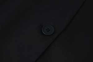 Close-up of matte black four-hole resin buttons and premium twill fabric on blazer