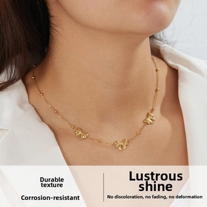 Close-up of gold-plated bead chain necklace with bow pendants on a female model neck