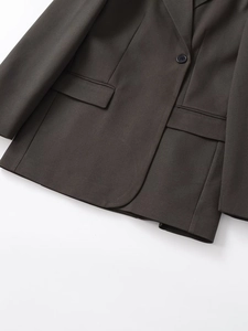 Detail of a slim-fit dark blazer showing single-button closure and flap pockets