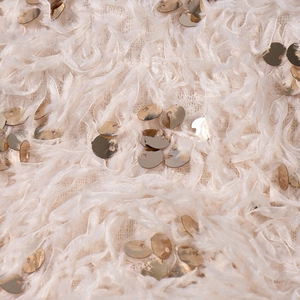 Dettaglio macro del tessuto piumato rosa beige con accenti di paillettes dorate lucide