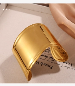 Macro detail of polished wide opening golden bangle with elegant mirror finish and smooth curves
