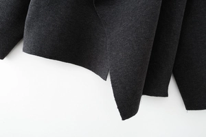 Close-up of side slit design and hem detail on a dark grey knitted fashion poncho