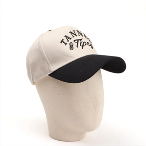 Detail of TANNED & Tipsy embroidery on a beige and black cotton baseball cap