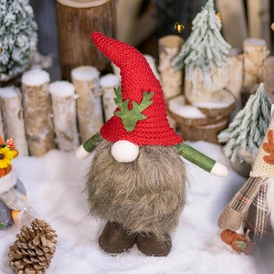 Handmade Christmas gnome with red knit hat and antlers in a festive winter forest setting