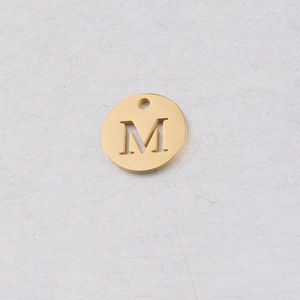 Gros plan d'un pendentif en acier inoxydable doré 12mm avec lettre M ajourée