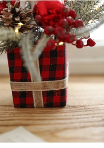 Detail of Christmas buffalo plaid base with pine cones, red berries and warm LED lights