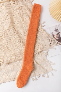 Detailed close-up of fluffy orange coral fleece over-the-knee socks for winter warmth