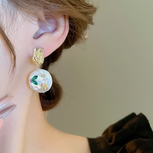 Detailed close-up of a vintage resin flower earring with pearl and green leaf accents