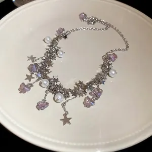 Collier papillon argenté élégant avec breloques étoiles et perles sur assiette blanche