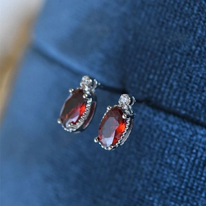 Macro shot of minimalist red oval gemstone earrings with white zircon accents