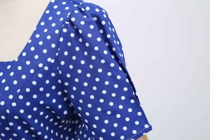 Detail of blue polka dot dress featuring a V-neckline and puff short sleeves on a mannequin