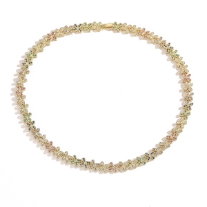 Macro shot of gold necklace links with colorful clover motifs and embedded gemstones