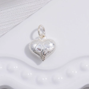 Macro detail of S925 silver heart pendant with textured grid and polished surface