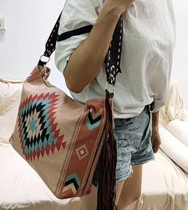 Detail of woven Bohemian tote bag featuring Aztec patterns and long leather tassels
