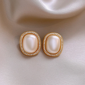 Detail of vintage gold pearl earrings with zircon inlay on champagne silk fabric