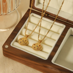 Elegant 18k gold shell pendants with sparkling crystals on warm wood and velvet background