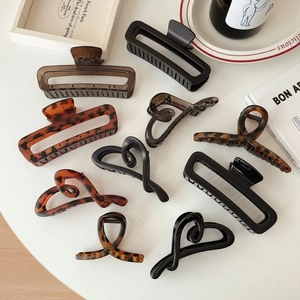 Elegant acetate claw clips in black, amber, and brown shown in various minimalist shapes