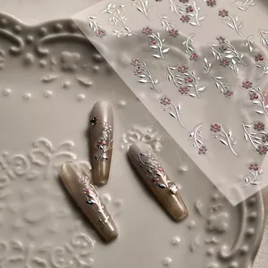 Detailed macro view of metallic silver floral nail art stickers on elegant long nails