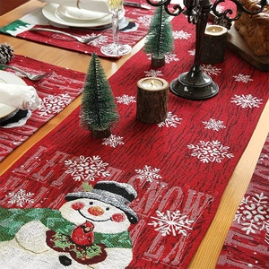 Detail of red Christmas table runner set with embroidered snowmen and festive patterns