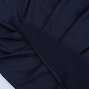 Macro detail of navy blue dress fabric featuring elegant cross-pleated textures and ruffles