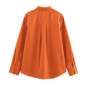 Detailed flat lay of an orange linen shirt featuring a back pleat and sharp stitching