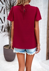 Detail of red polka dot chiffon top featuring a delicate back neck tie and floral lace trim