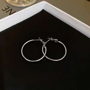 Boucles d'oreilles créoles en argent dans un écrin blanc minimaliste sur velours noir