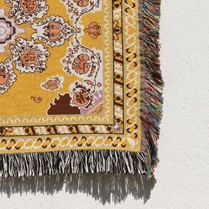 Macro detail of yellow bohemian woven blanket with floral patterns and colorful tassels