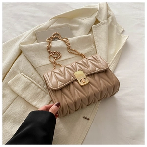 Detail of beige quilted chain bag with gold twist-lock on white blazer background