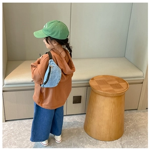 Close-up of children's blue denim crossbody bag paired with a brown hoodie and green cap