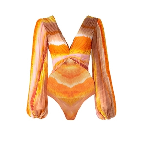 Detail of V-neck tie-dye long sleeve swimsuit showing orange and beige wavy patterns