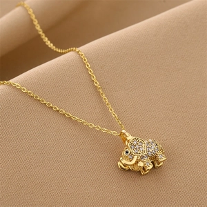 Golden elephant pendant necklace with zircon crystals on warm textured fabric