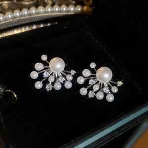Macro shot of elegant silver pearl fireworks earrings on a black velvet jewelry box