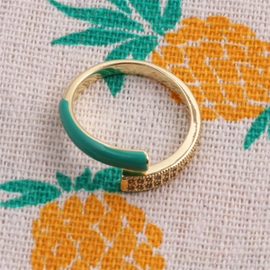 Detail of gold adjustable ring with green enamel finish and zircon stone accents