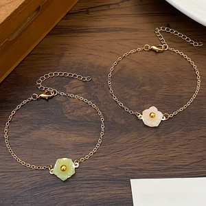 Detail of adjustable gold bracelets with light green and cream resin flower charms